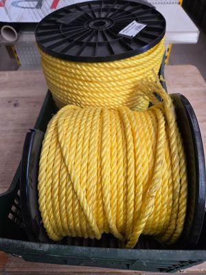une corde torsadée jaune dans un panier posé sur une table, à côté d'une paire de ciseaux