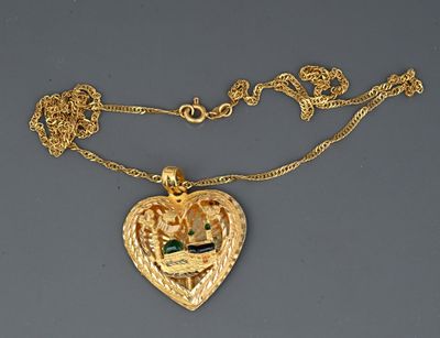 a close up of a gold necklace with a heart shaped pendant on a chain