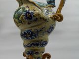 a blue and yellow vase with a handle on a stand