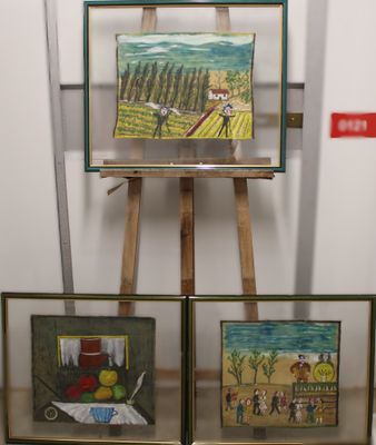 paintings on easel in front of a white wall in a room