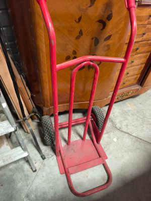 a red hand truck that is sitting in front of a dresser