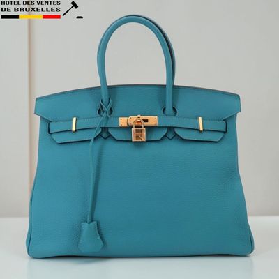 un sac à main en cuir bleu muni d'un fermoir doré sur la poignée