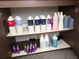 many bottles of hair products on a shelf in the bathroom