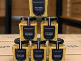 une pile de six pots de moutarde posée sur une boîte en carton