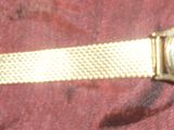 un gros plan d'une montre en or posée sur un tissu rouge