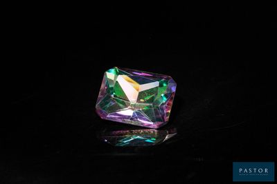 a close up of a colorful crystal stone on a black surface