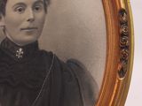 an old picture of a woman in a black dress in a gold frame