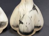 two vases with birds painted on them sitting on a table