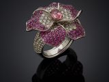 a pink and white diamond flower ring on a black surface