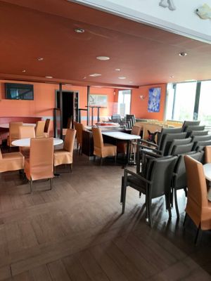 tables and chairs in a restaurant with orange walls and wood flooring