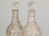 two glass bottles sitting on a table with a white background