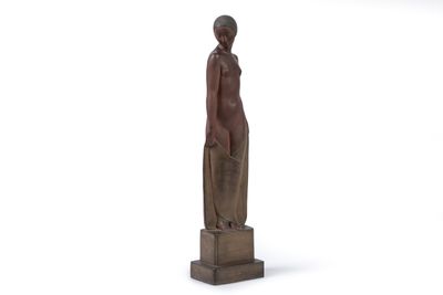 statue d'une femme debout sur un socle en bois, les mains dans les poches