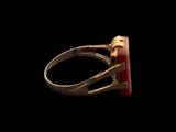 an image of a gold ring with a red stone in it