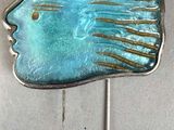 une broche en forme de poisson bleu fixée à une épingle en argent