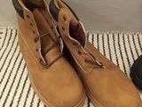 pair of men ' s brown leather boots on a striped rug