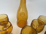 bottles and glasses sitting on a table with a vase in the background