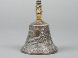 a silver bell with a bird on top of it sitting on a table