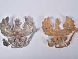 two gold colored brooches on a white surface