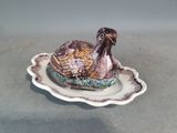 un oiseau en céramique posé sur une assiette posée sur une table
