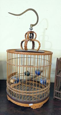 a bird in a cage on a table next to other bird cages
