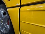 a close up of a yellow car parked in a parking lot