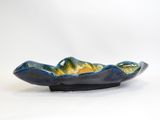 blue and yellow ceramic bowl on black stand against a white background