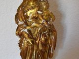 gold statue of a woman holding a child on a wooden table