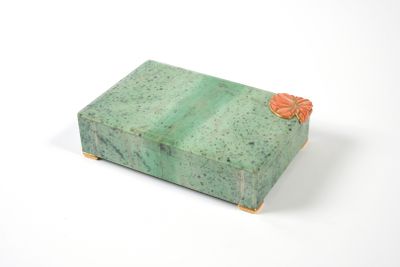 green marble box with orange flowers on top on a white surface