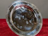 an antique silver plate with beaded edge on a red velvet surface