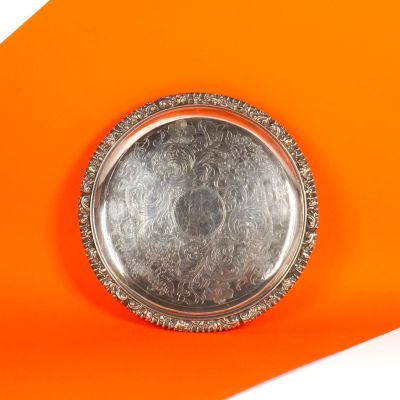 une assiette en argent posée sur une surface orange avec un fond blanc