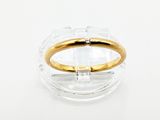 une image représentant une bague dorée et transparente posée sur une surface transparente