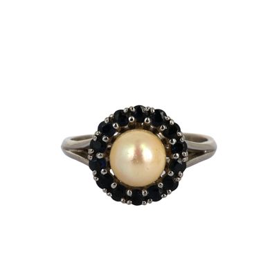 un gros plan d'une bague ornée d'une perle et d'un diamant noir sur fond blanc