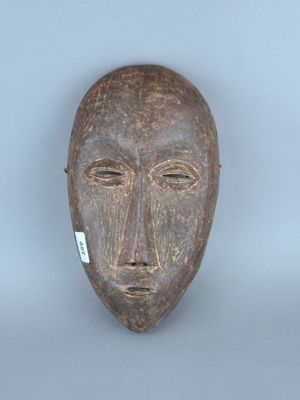 une image représentant un masque en bois sur lequel est accrochée une étiquette