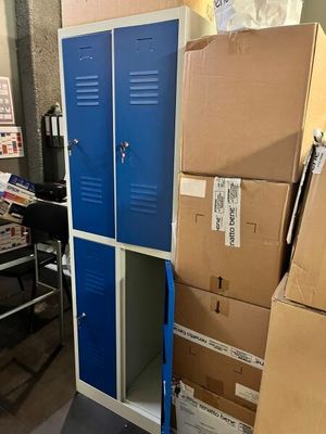 une pile de cartons posée par terre à côté d'un casier bleu