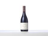 a bottle of red wine sitting on top of a white table