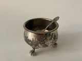 an old silver bowl with a spoon sitting on top of it
