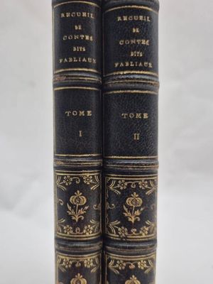 two black books with gold trims are stacked on top of each other