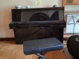un piano et un tabouret dans une pièce où est accroché un tableau au mur
