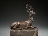 bronze sculpture of a deer lying down on a marble block