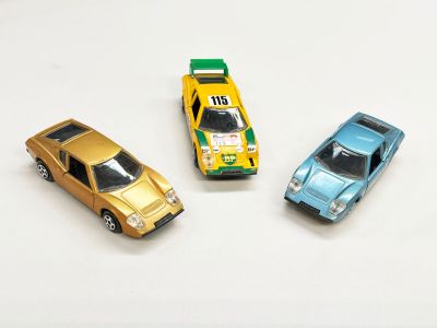trois petites voitures assises l'une à côté de l'autre sur une surface blanche