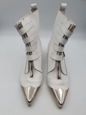 une paire de bottes en cuir blanc avec des talons en métal argenté sur une surface blanche