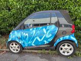 a small car that is painted with graffiti on the side of the road