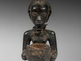 une statue en bois représentant une femme tenant un bol dans ses mains