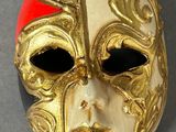 gold mask with red accents on a gray surface