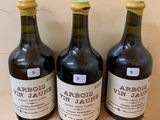 three bottles of wine sit on a wooden shelf in front of a wall