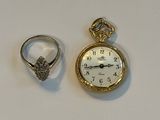 deux bagues et une montre de poche posées sur une table