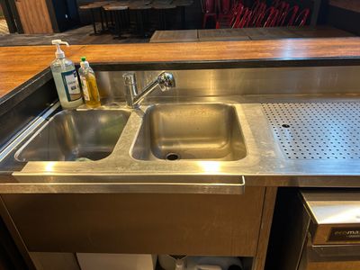 a stainless steel sink in a kitchen with a wooden counter top