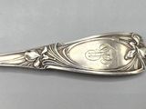 silver plated spoon with floral design and a monogram on the handle