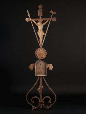 une vieille sculpture en fer représentant un homme tenant une croix au bout d'un mât