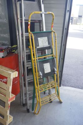 une échelle appuyée contre un mur, à côté d'une pile de caisses
